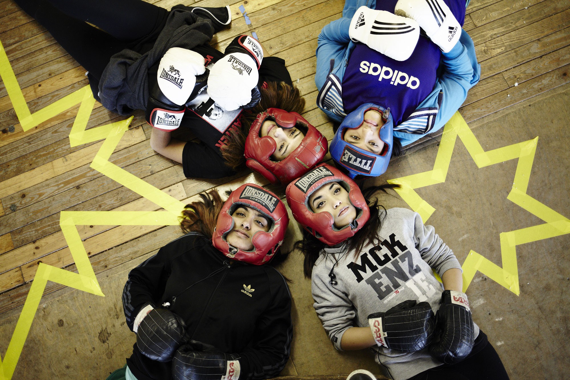 Performers from the site-specific theatre piece No Guts No Heart No Glory, about female muslim boxers, in boxing gear lying on the floor.