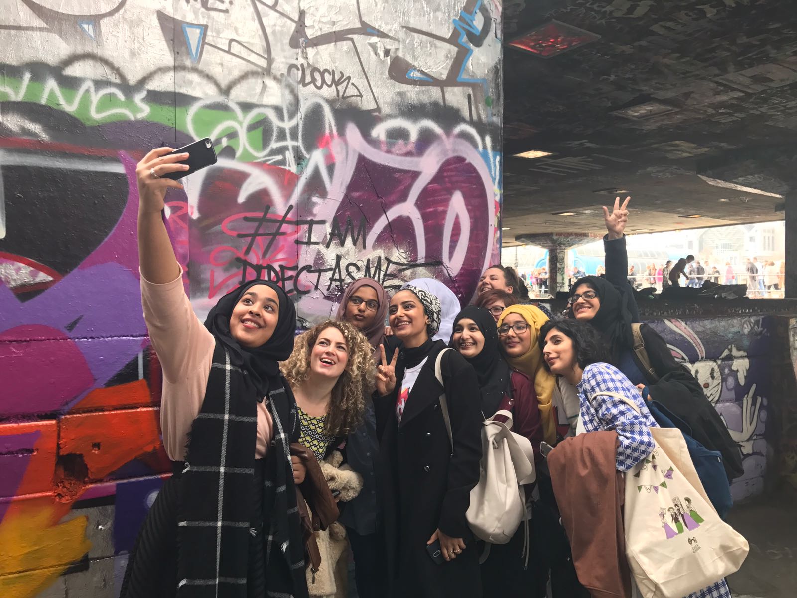 A selfie of the Speakers Corner girls at the southbank centre underground skatepark, in front of some graffiti.