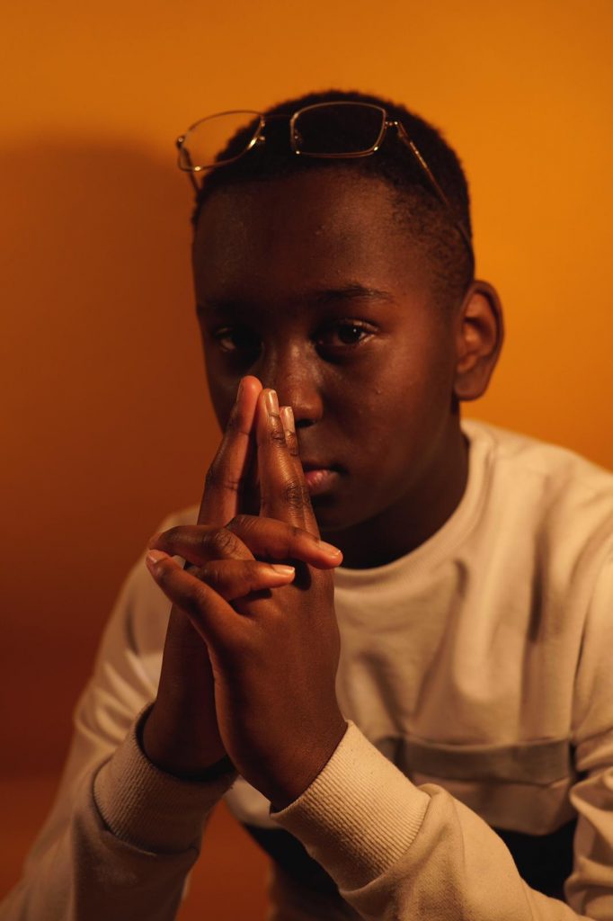 Portrait of a young boy who holds his fingers to his face