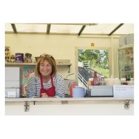 Smiling woman in cafe van wearing a red apron