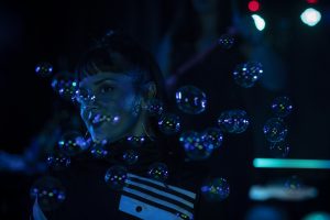 Girl in tracksuit with bubbles blown at her
