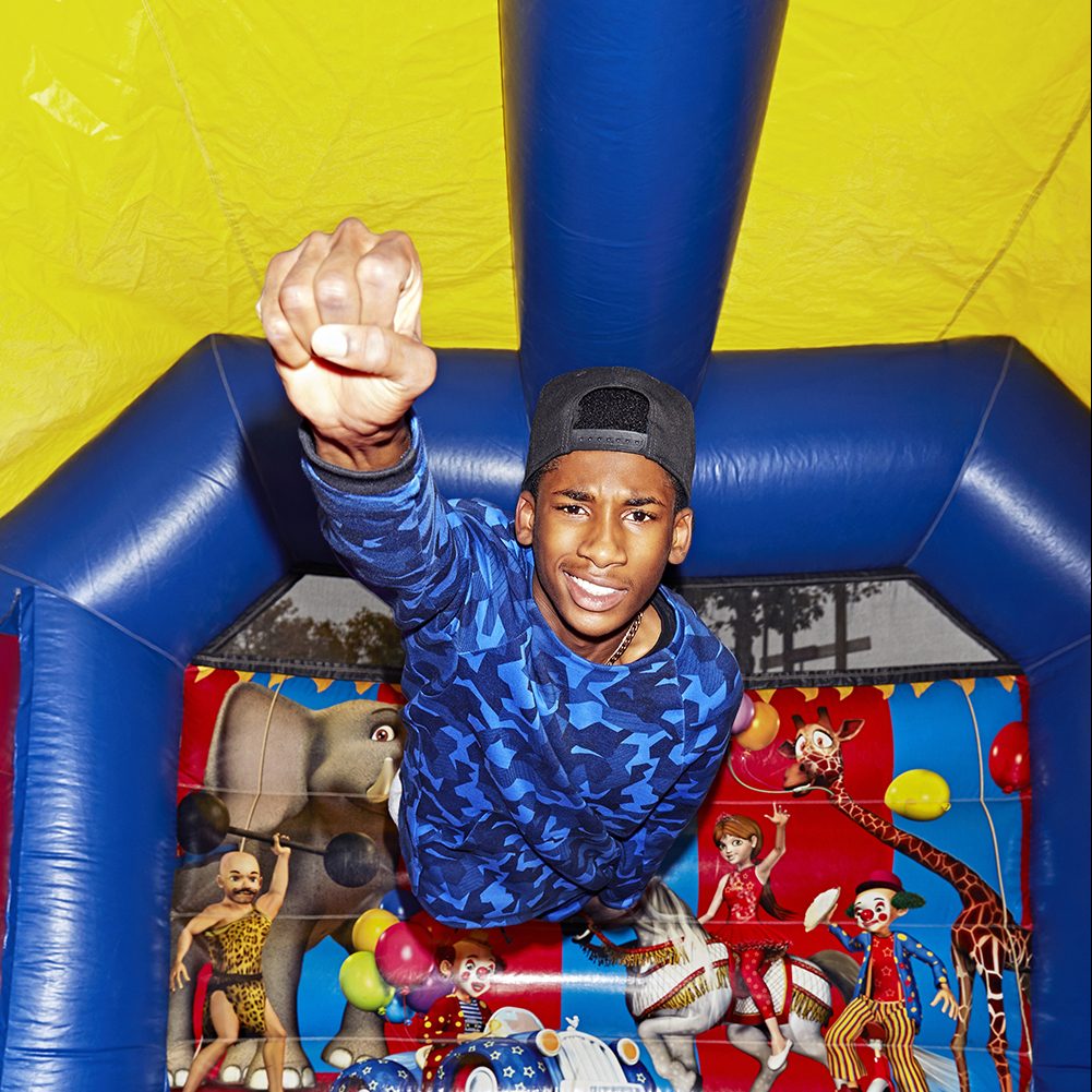 A young man flies like superman in a bouncy castle