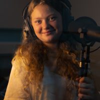 girl wearing headphones singing into a mic