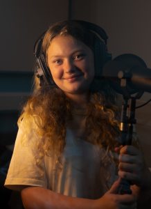 girl wearing headphones singing into a mic