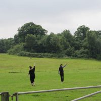 Two people walk across a field with their arms raised