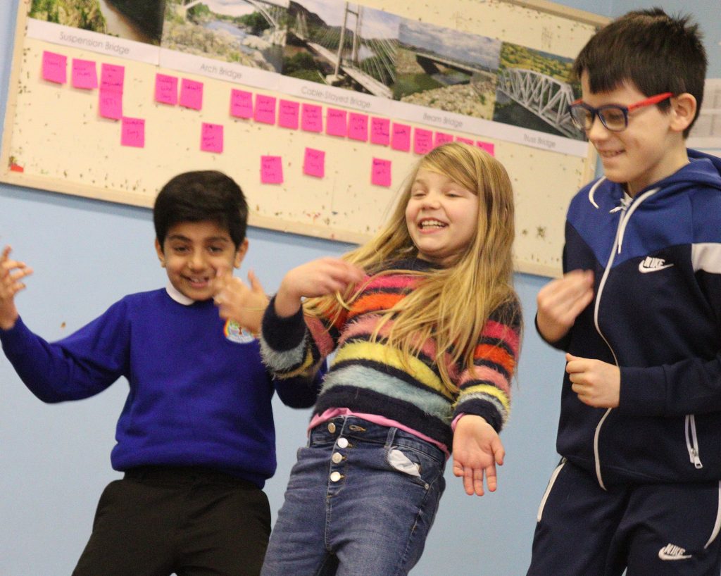 Three children stand, leaning backwards. They look like they are having fun.