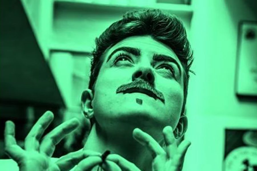 Photographic portrait in green and black of drag king Len Blanco