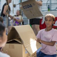 A girl makes a house out of cardboard boxes