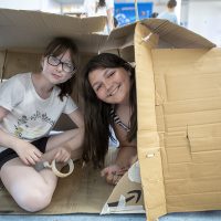 Two girls hide inside a cardboard box