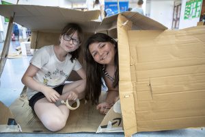 Two girls hide inside a cardboard box