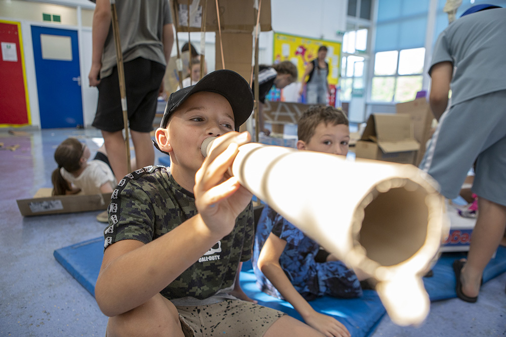 A boy holds a cardboard tube to his mouth
