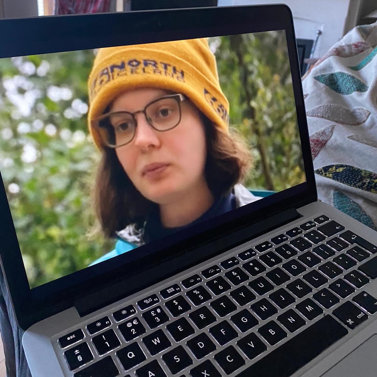 Photo of a image of a woman wearing a yellow woolly hat, on a laptop screen