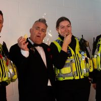 A community police officer and a man in a tuxedo enjoy themselves