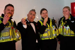 A community police officer and a man in a tuxedo enjoy themselves