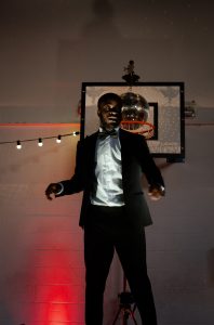 A young man, in a tux, dances on a podium