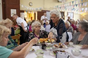 Older ladies help themselves to scones and cakes at a tea party