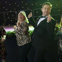 A man in a tuxedo dances with a woman in a leopard print top