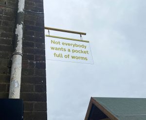 A sign hung outside which says "not everybody wants a pocket full of worms"