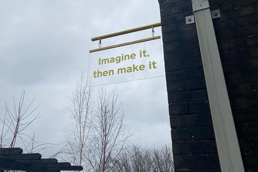 A sign, hung outside which says in yellow 