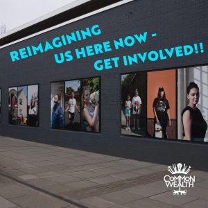 An image of a walkway with large photographs of people in the windows. The words "Reimiagining Us Here Now - Get involved" are superimposed in blue