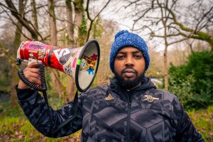 Man sits in a forest with a loudspeaker