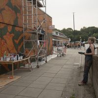 Helen Bur stands back and looks at the mural in progress