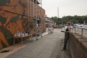 Helen Bur stands back and looks at the mural in progress