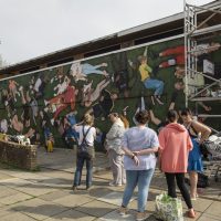 People stand looking at the mural