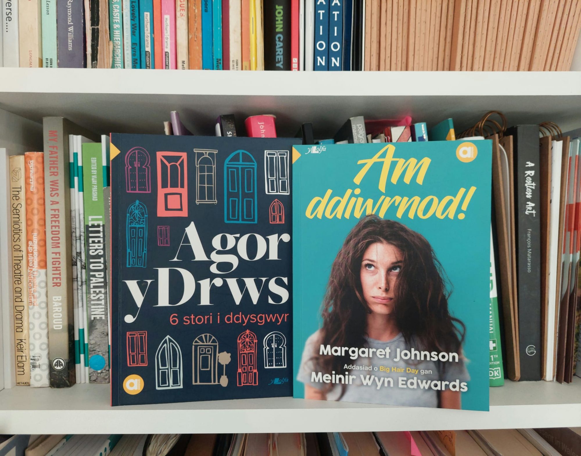 Two Welsh language books, aimed at learners, on a bookshelf.