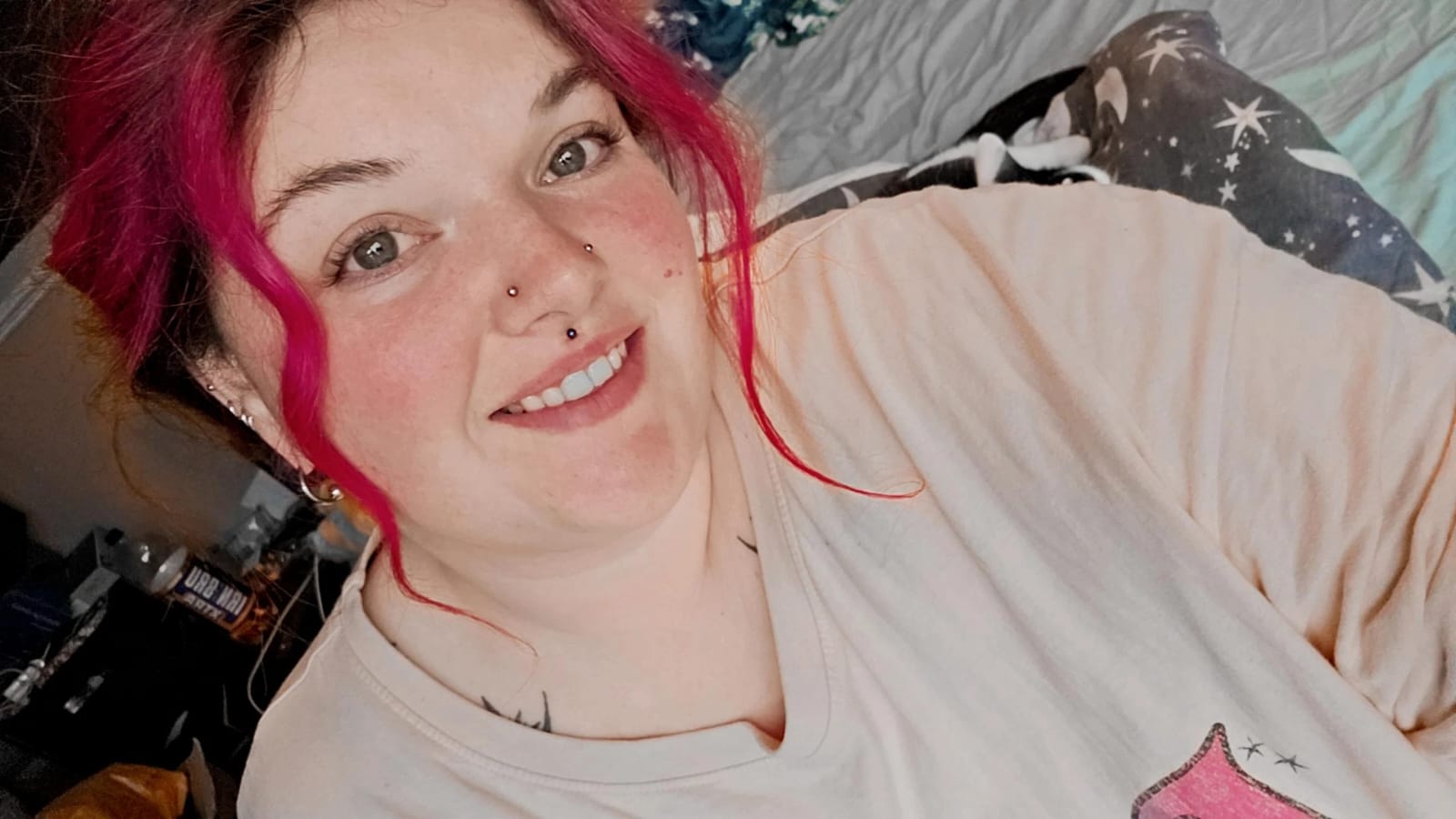 A photo of a woman with pink hair. She's smiling.