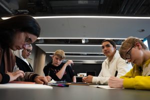 A group of five young people are concentrating on a group task. They are a mixed group in terms of age, race and gender.