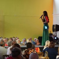 Singer Emilie Parry-Williams sings on a stage as a crowd of older people watch