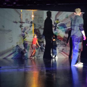 Performers interact with colourful projection of protest footage