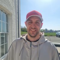 Man with baseball cap smiling at the camera at Llanrumney Hall.