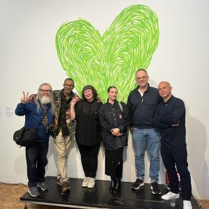 Artists and creatives involved in the project, with the Grenfell green heart behind them.
