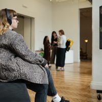 Audience member wearing headphones to watch art piece.
