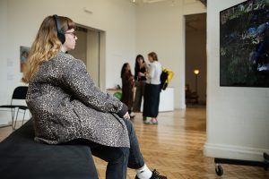 Audience member wearing headphones to watch art piece.