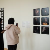 Audience member photographing photography on the wall.