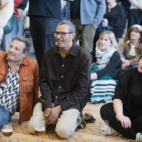 Audience members sitting on the floor and listening to poetry.