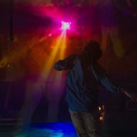Actor Soul Roberts dances in front of bright pink and orange lights 