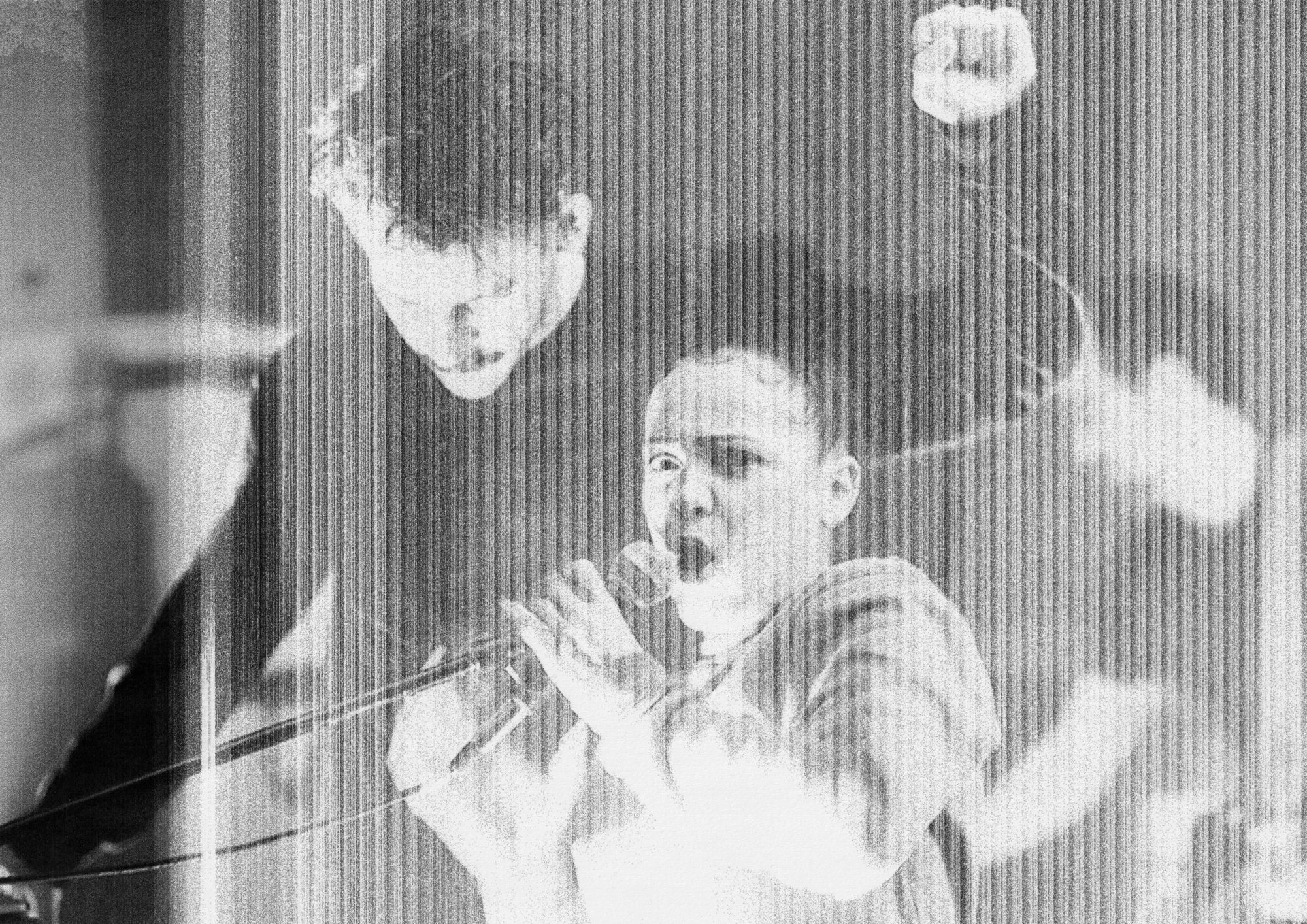 A distorted image of a woman shouting into a microphone with a man dancing behind her
