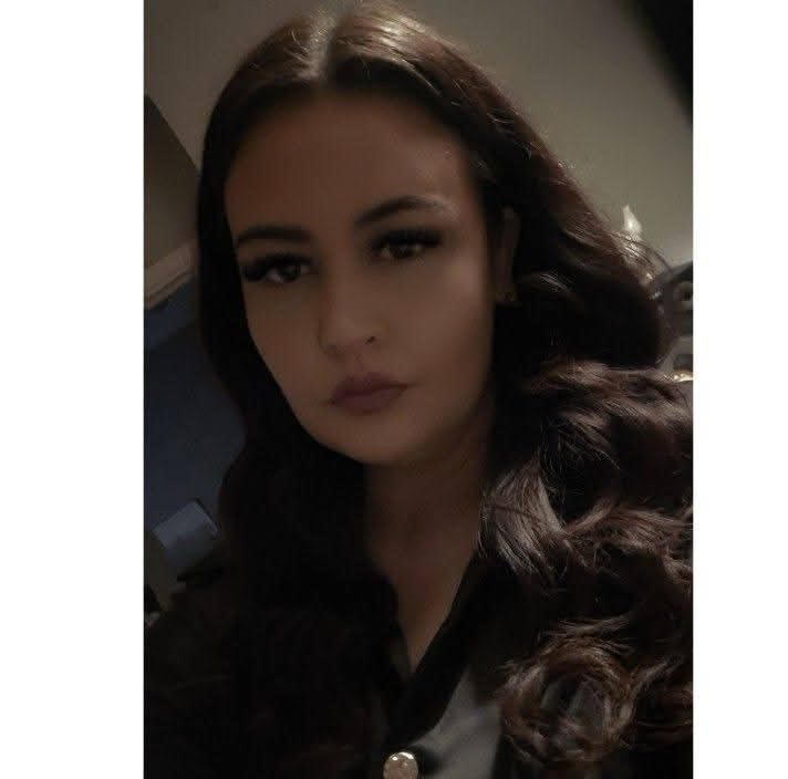 A close-up selfie style picture of Janine Newbury. Janine has long dark hair, dark eyelashes and is wearing a neutral lipstick.